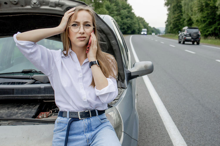 Eine Frau steht am Straßenrand, weil jemand ihr dike Vorfahrt genommen hat und ihr Auto nun Schäden hat. Sie kontatkiert für eine kostenlose Erstberatung den KFZ Sachverständigen Jörg Langer in Herne.