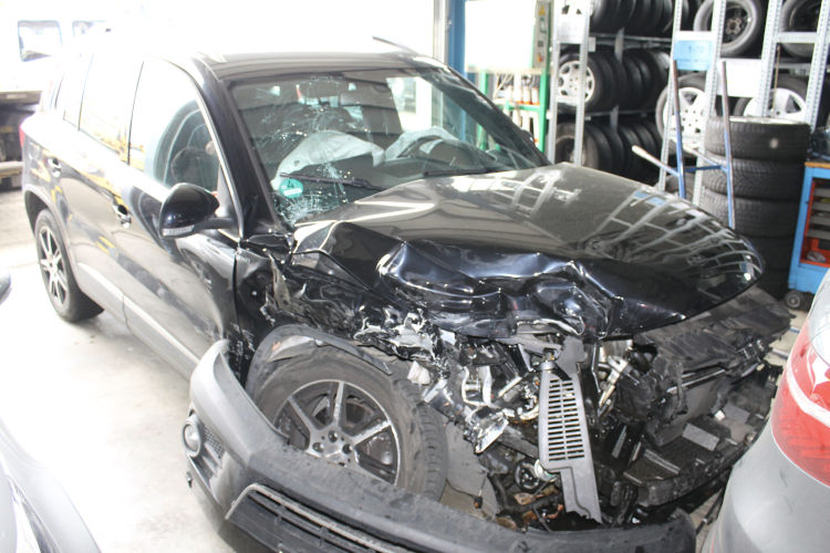 Volkswagen Tiguan mit völlig zerstörter Front und ausgelöstem Airbag als Totalschaden in einer Werkstatt. KFZ Sachverständiger ermittelt den Wiederbeschaffungswert